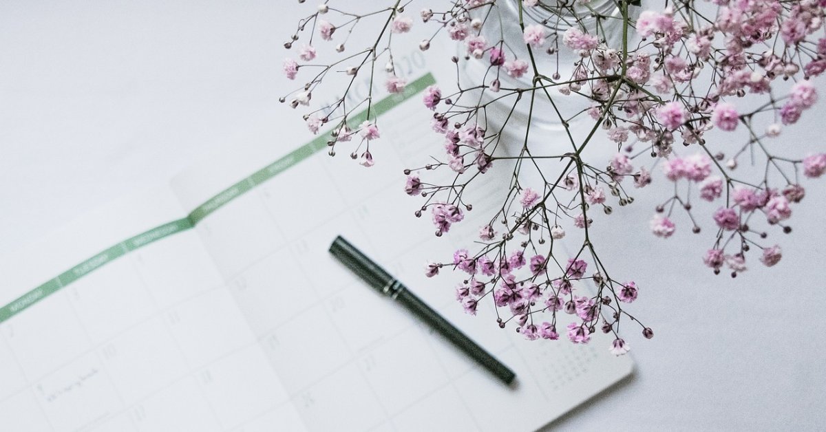 Open agenda met een pen en een tak met roze bloesem